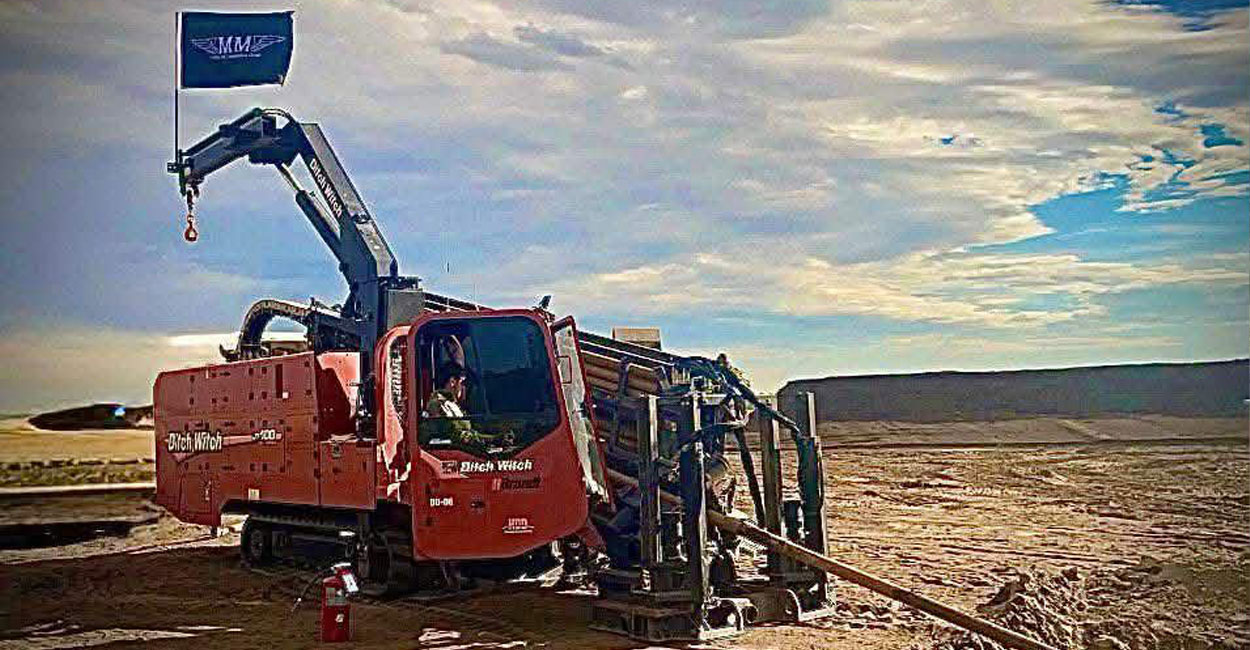 A directional drilling rig prepares for an underground utility installation in an open field.