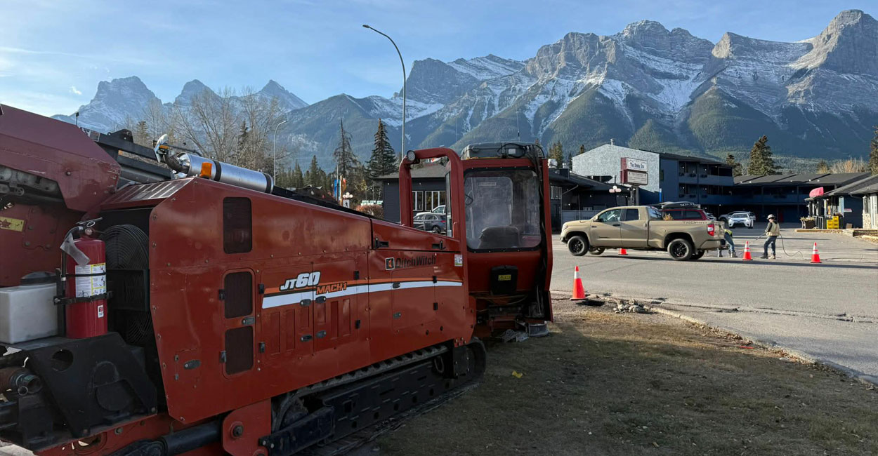 An HDD machine works on a utility project in downtown Canmore, Alberta, with the Rockies in the background.